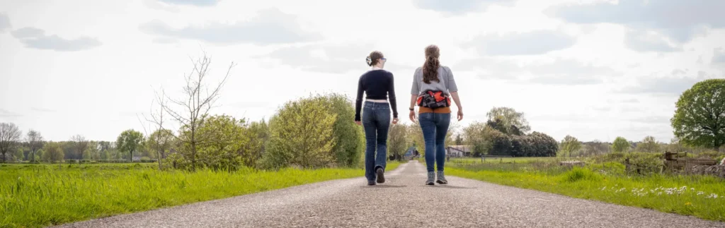 Counseling Services - Life Giving Counseling 5 Two women walking side by side on a country road, symbolizing person-centered therapy at Life Giving Counseling.